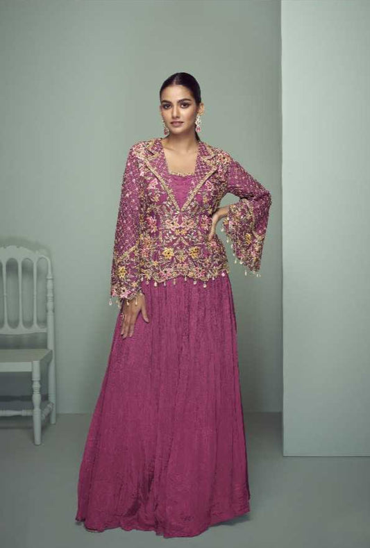 Woman wearing a pink traditional outfit with intricate designs, sitting on a chair against a plain background. Gulkayra brand visible.