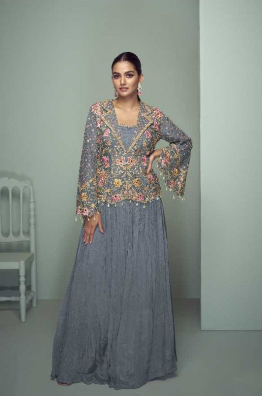 Woman wearing a gray traditional outfit with floral patterns, standing against a light green background. Gulkayra brand visible.