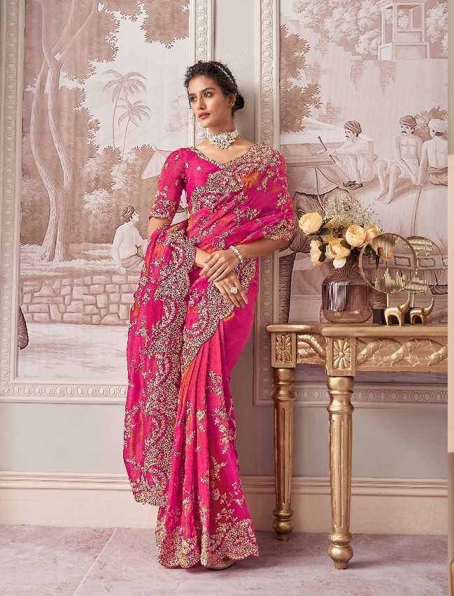 Woman wearing a pink saree with gold embroidery in an elegant room.