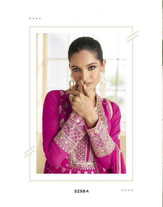Woman in a pink traditional outfit with intricate designs in a well-lit room.