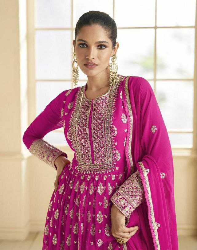 Woman wearing a pink traditional outfit with intricate designs in a bright room.