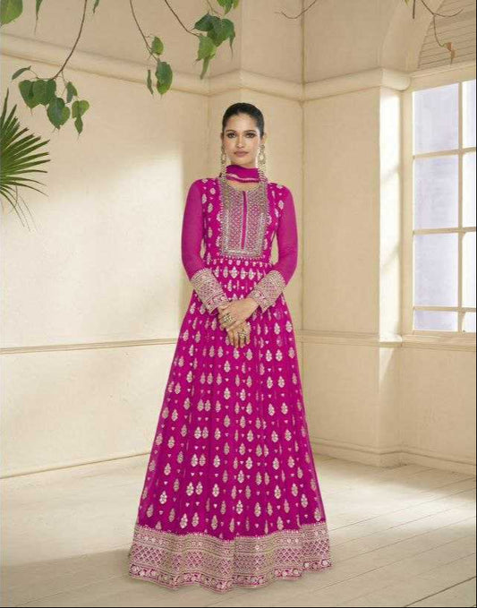 Woman in a pink traditional outfit with intricate designs in a well-lit room.