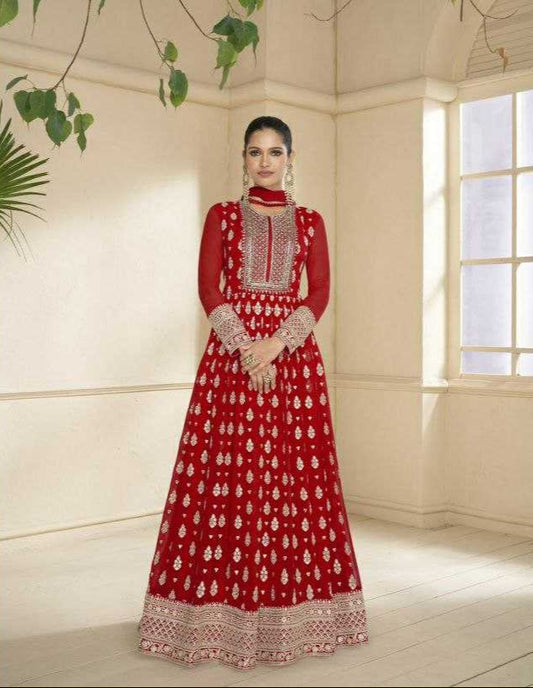 Woman in a red traditional outfit with intricate patterns in a well-lit room.