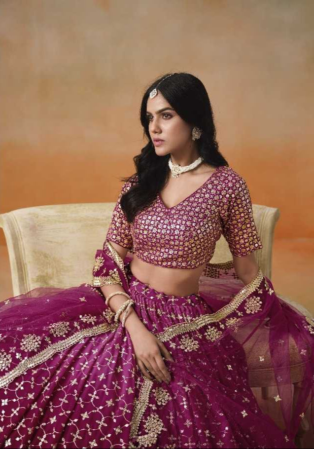 Woman wearing a traditional pink embroidered outfit with a matching dupatta on an orange background.