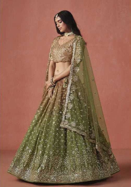Woman wearing a traditional green and gold embroidered outfit against a pink background