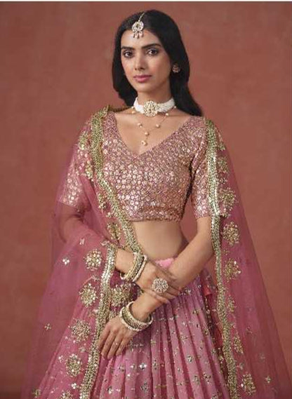 Woman wearing a pink embroidered traditional outfit against a brown background