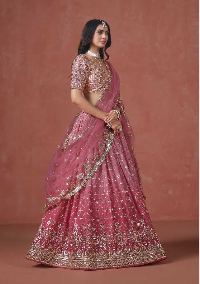Pink embroidered saree with gold details worn by a model on a brown background