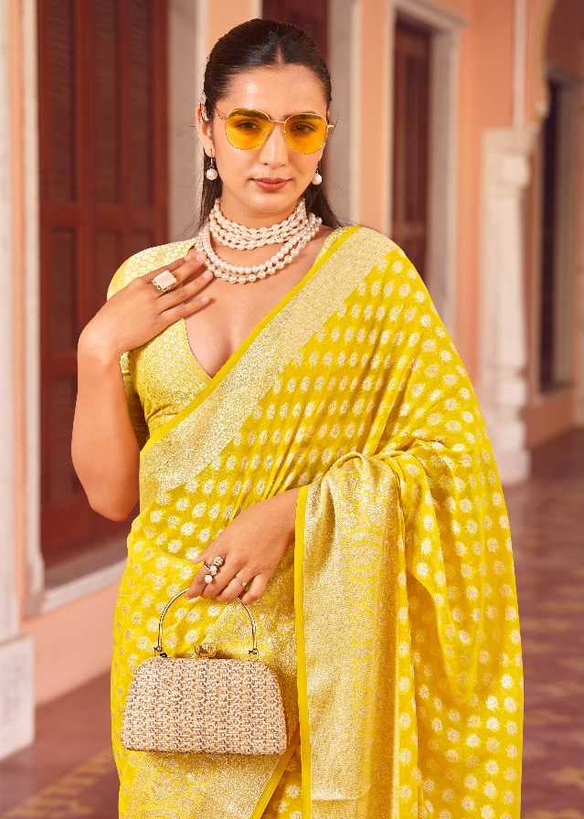 Woman in a yellow saree with a matching blouse, sitting in a hallway.