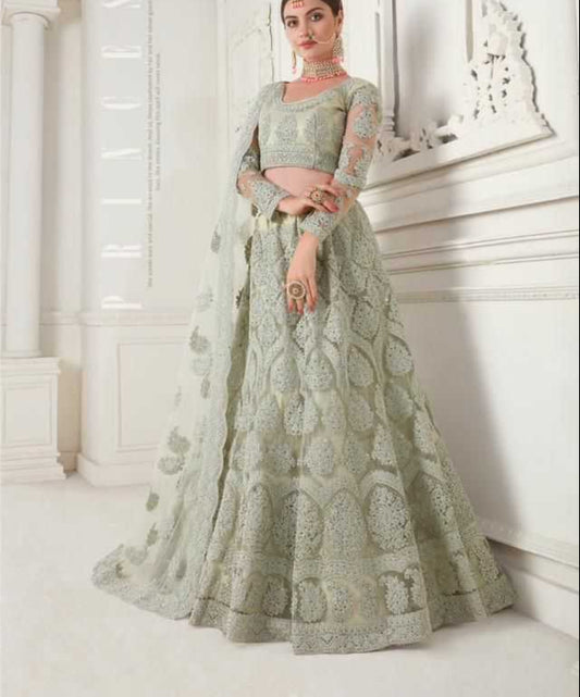 Woman in a green embroidered lehenga with a white background
