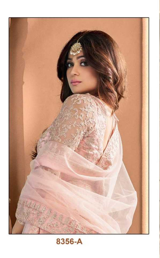 Woman wearing a pink embroidered dress with a matching dupatta in an indoor setting.