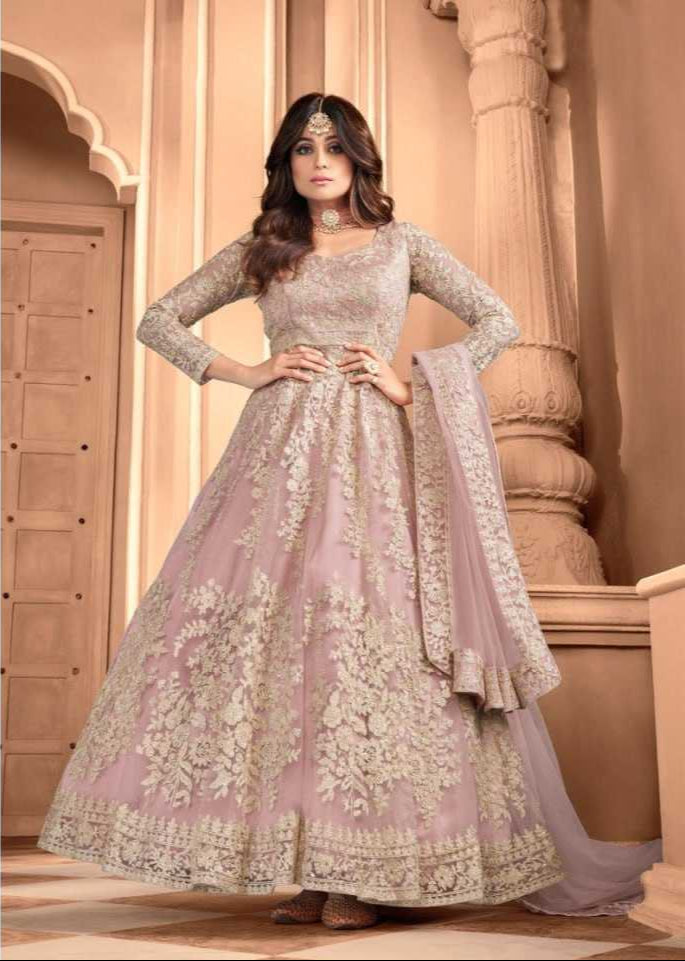 Woman wearing a traditional embroidered pink gown with a beige background