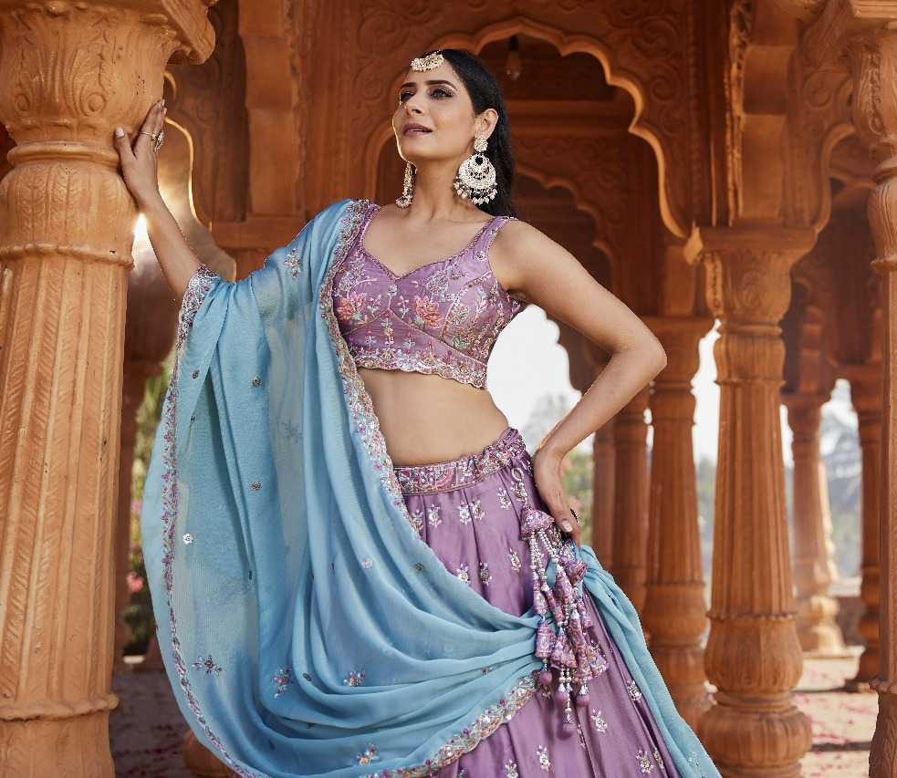 Woman in traditional attire standing in an architectural setting with ornate columns.