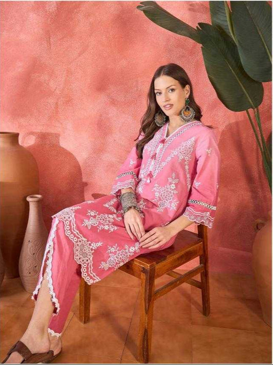 Woman wearing a pink embroidered outfit against a pink background with decorative elements.