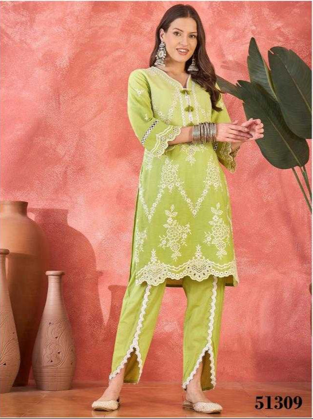 Woman in a green traditional outfit with white embroidery against a pink background