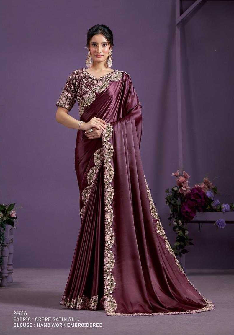 Woman wearing a maroon saree with gold embroidery against a purple background