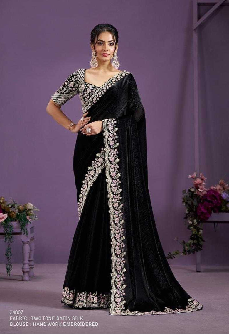 Woman wearing a black saree with silver embroidery against a purple background