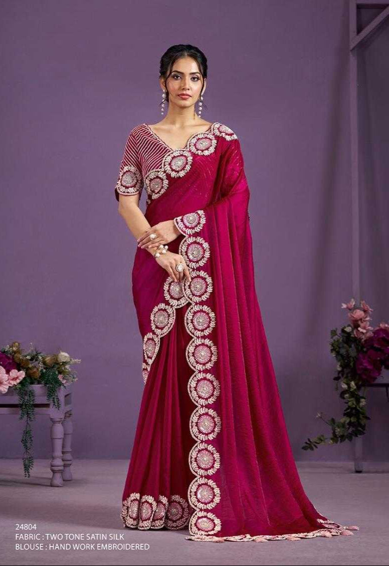 Woman wearing a red saree with intricate gold patterns against a purple background
