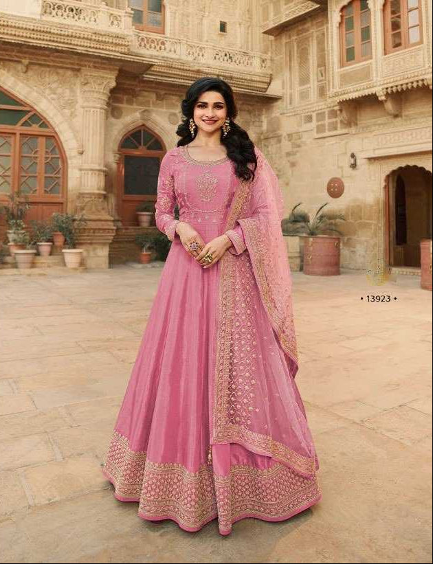 Woman in a pink traditional outfit with a matching dupatta, standing in an outdoor setting.