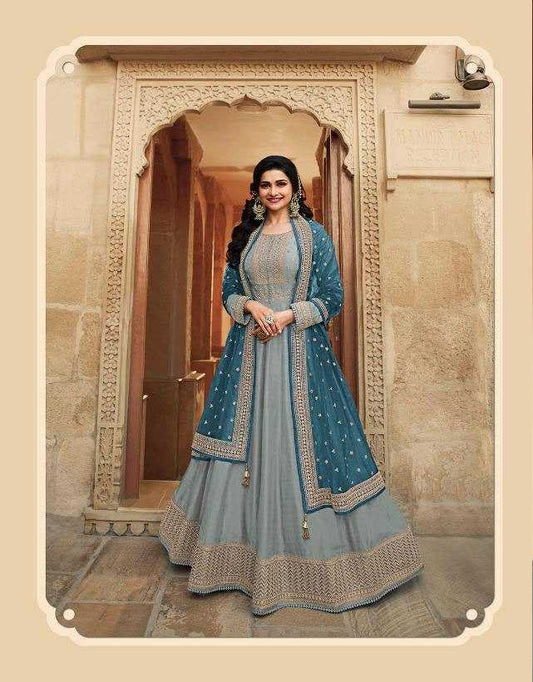 Woman in a traditional blue and gray outfit standing in an ornate doorway.