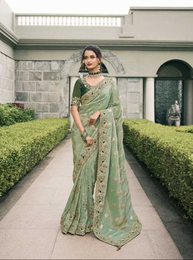 Woman in a green saree with a matching blouse, standing outdoors.