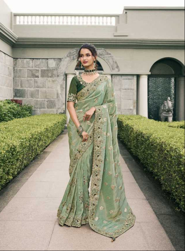 Woman in a green saree with a matching blouse, standing outdoors.