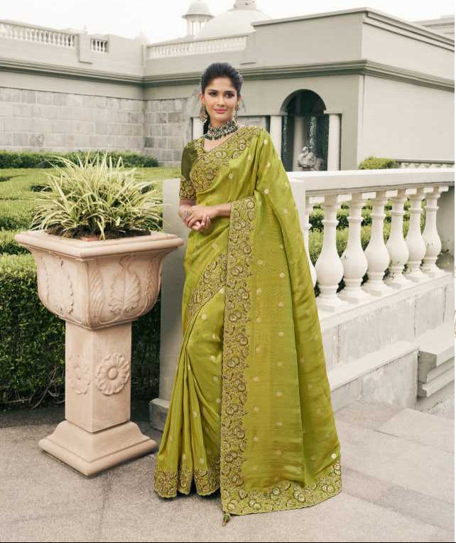 Woman in a green saree with gold embroidery standing outdoors.