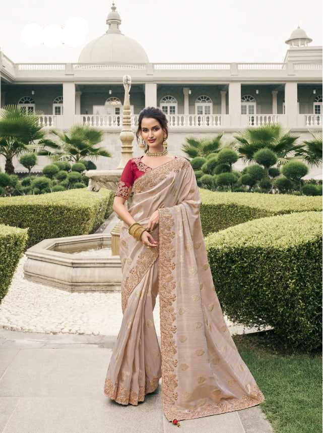 Woman in a beige saree with a red blouse standing in a garden setting.