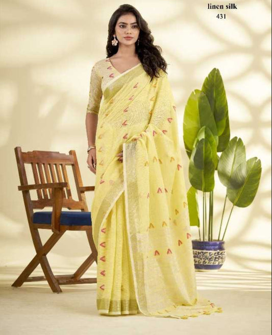 Woman in a yellow saree with subtle patterns, sitting on a chair in a softly lit room.