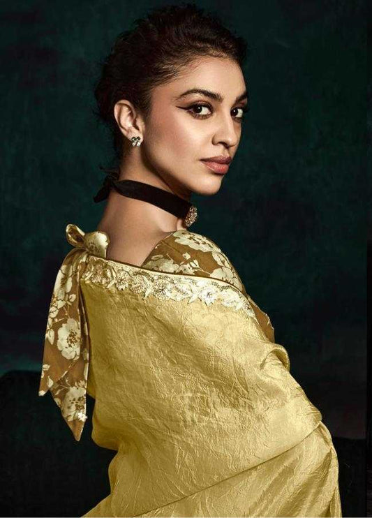 Woman in a gold saree with intricate designs against a dark background