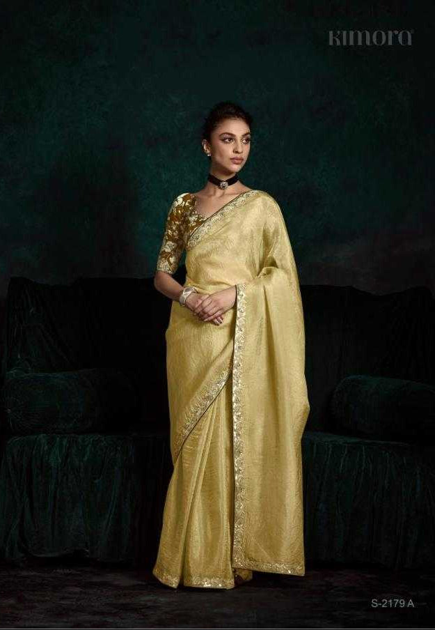 Woman in a gold saree with intricate designs against a dark background