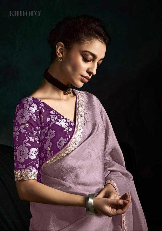 Woman wearing a purple and pink saree with a dark background