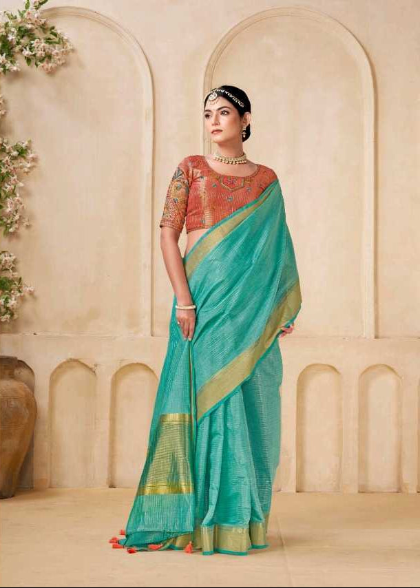 Woman wearing a turquoise saree with a green border in an indoor setting.