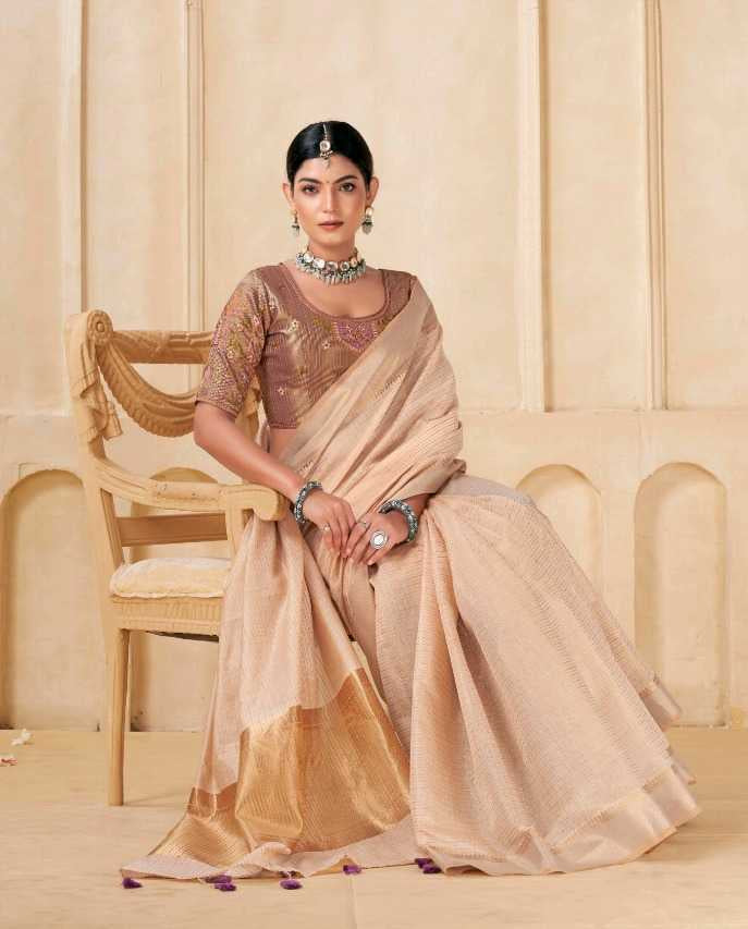 Woman in a saree sitting on a chair with a decorative wall in the background