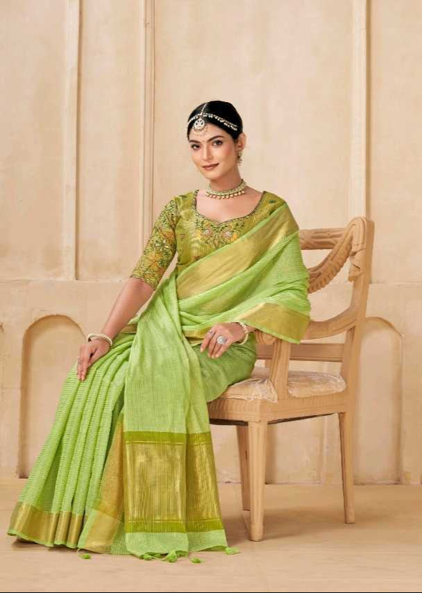 Woman in a green saree sitting on a chair with a neutral background
